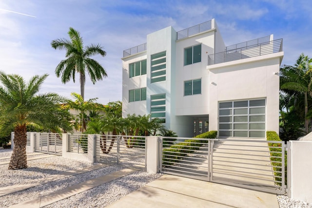 view of front of home with a fenced front yard, a gate, a balcony, and driveway