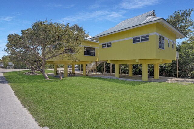 rear view of property featuring stairs and a lawn