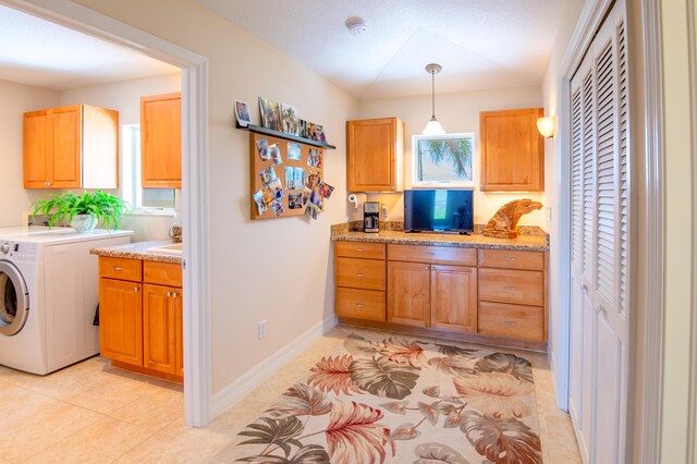 kitchen featuring washer / clothes dryer, pendant lighting, light tile patterned flooring, and baseboards