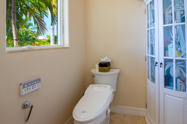 bathroom with toilet, tile patterned floors, and baseboards