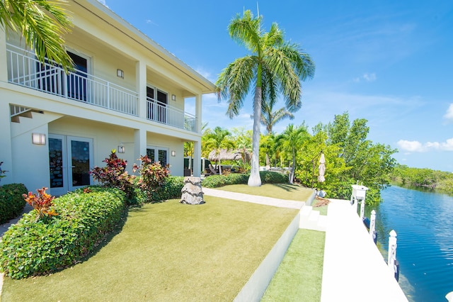 view of yard featuring a water view, a balcony, french doors, and a dock