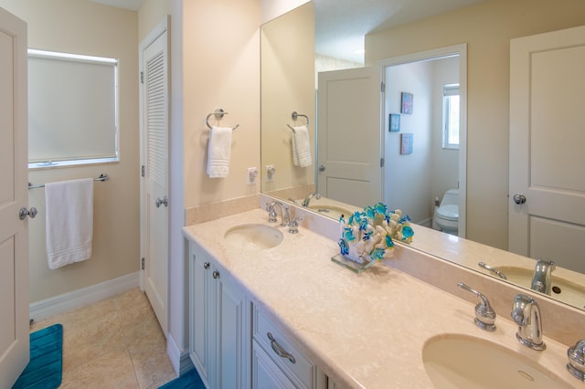 bathroom featuring a sink, tile patterned floors, double vanity, and toilet