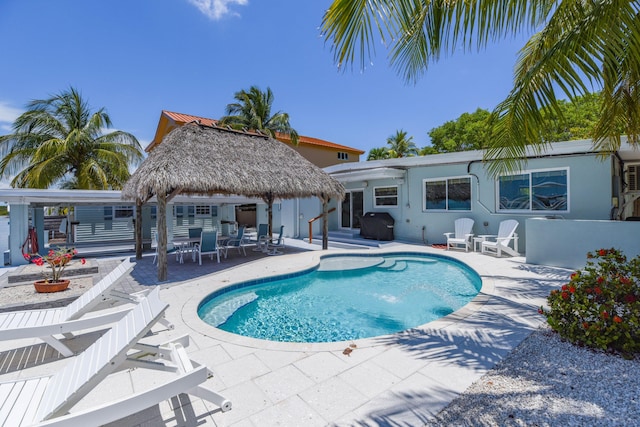 pool featuring a gazebo, grilling area, and a patio area