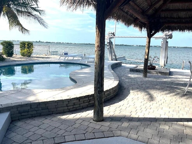 outdoor pool with a water view and a patio