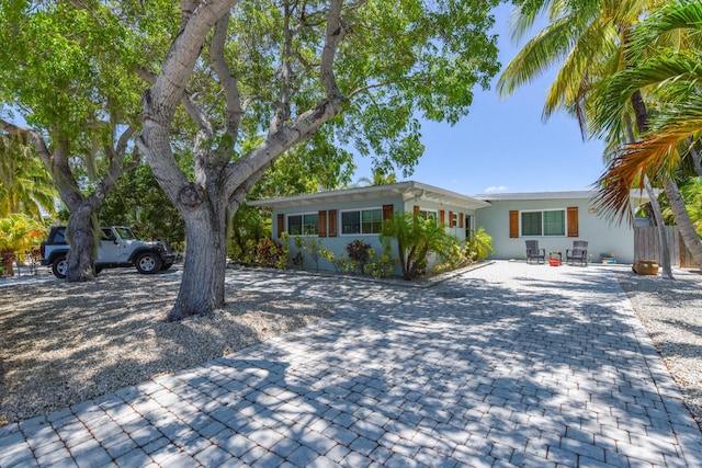 ranch-style home featuring decorative driveway and fence