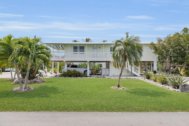 beach home with a carport, a porch, stairs, and a front lawn