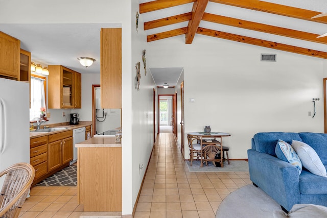 kitchen featuring open floor plan, lofted ceiling with beams, light tile patterned floors, white appliances, and a sink