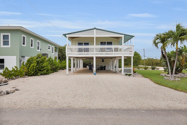 coastal inspired home featuring a carport and gravel driveway