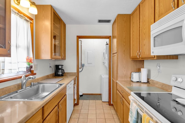 kitchen with white appliances, visible vents, washer / dryer, a sink, and brown cabinets