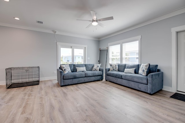 living area with visible vents, ornamental molding, light wood-style floors, ceiling fan, and baseboards