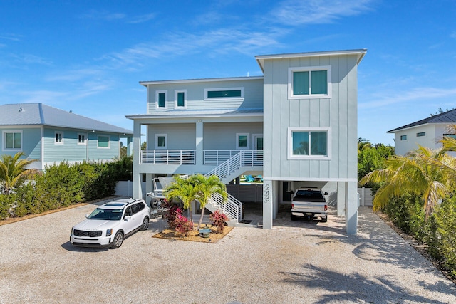 view of front of property featuring a carport, dirt driveway, stairway, board and batten siding, and metal roof