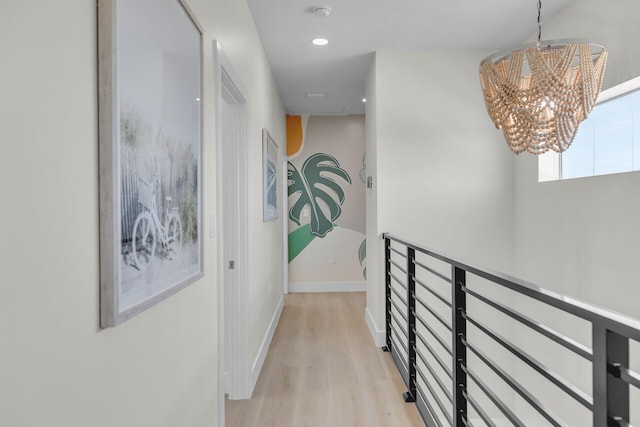 hallway with light wood-style floors, an inviting chandelier, baseboards, and recessed lighting