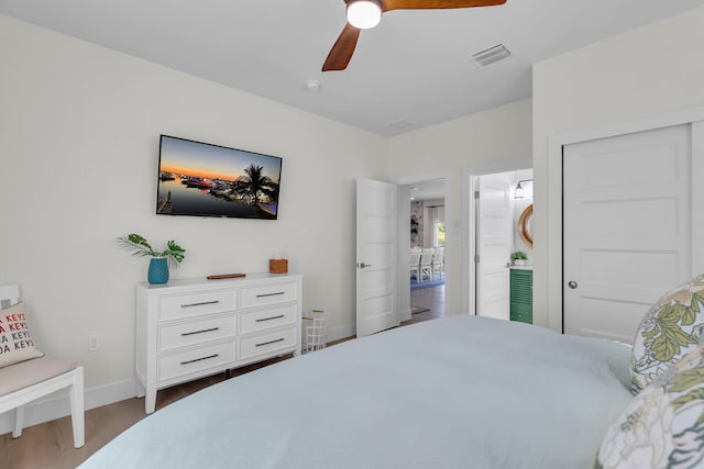 bedroom featuring visible vents, baseboards, a ceiling fan, and wood finished floors