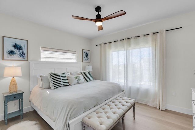 bedroom with light wood-type flooring, baseboards, and a ceiling fan