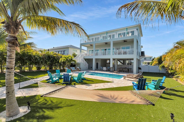 back of house featuring a ceiling fan, a lawn, a patio, stairs, and a balcony
