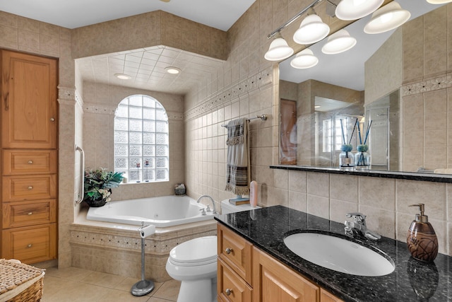 bathroom featuring tile patterned flooring, toilet, vanity, tile walls, and a whirlpool tub