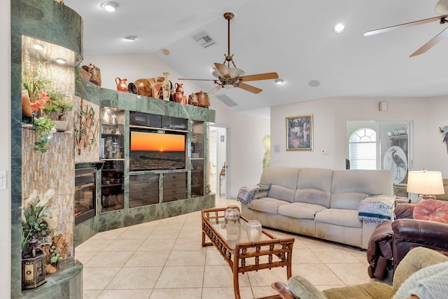 living room with light tile patterned floors, visible vents, a tile fireplace, lofted ceiling, and ceiling fan