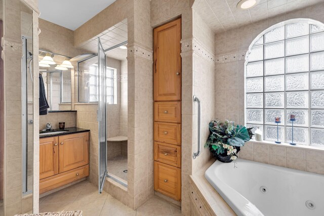 bathroom featuring a tub with jets, tile patterned floors, vanity, a shower stall, and tile walls