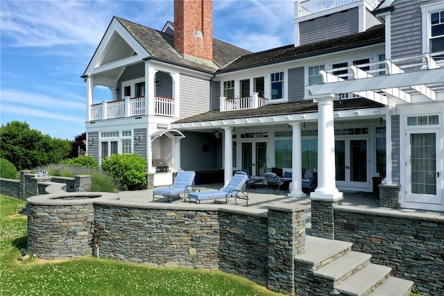 rear view of house with area for grilling, a balcony, a patio, and french doors