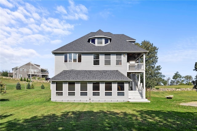 rear view of house featuring a yard and a balcony