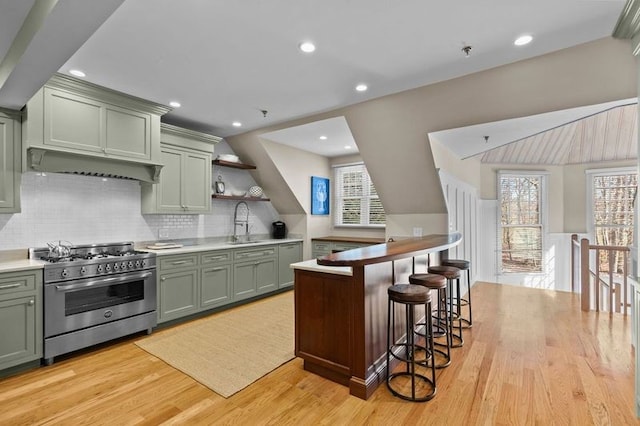 kitchen featuring light hardwood / wood-style flooring, high end stainless steel range oven, and green cabinetry