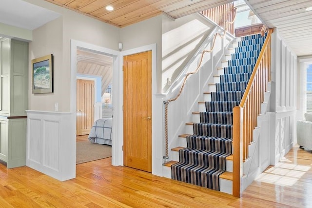 stairs with a healthy amount of sunlight, wood-type flooring, and wood ceiling