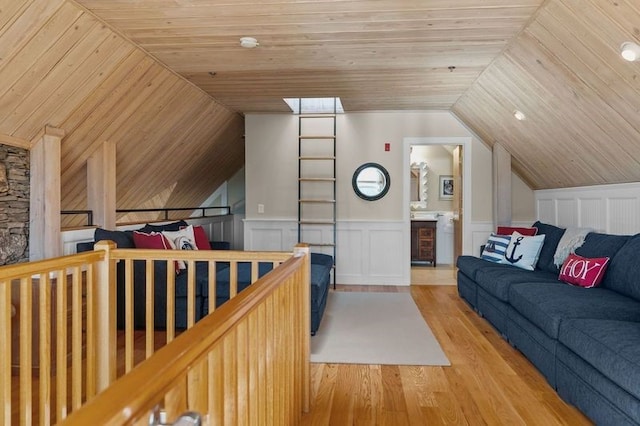 living room with light hardwood / wood-style floors, wood ceiling, and vaulted ceiling with skylight