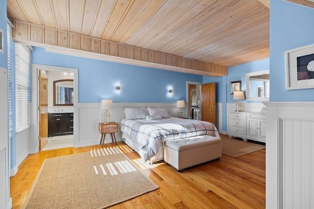 bedroom with connected bathroom, wooden ceiling, and light wood-type flooring