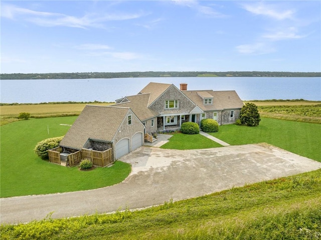 view of front of property featuring a garage, a water view, and a front lawn