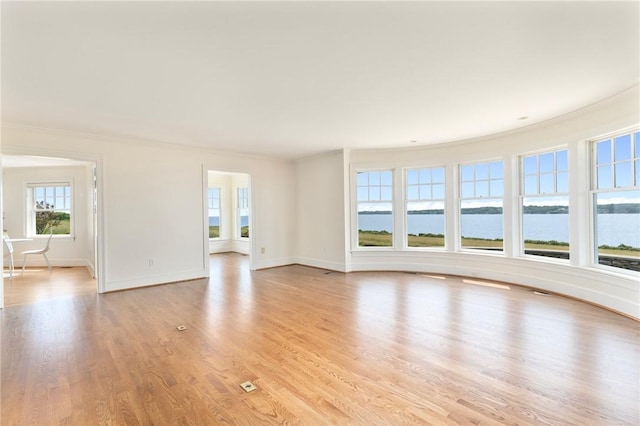 unfurnished living room with ornamental molding, light hardwood / wood-style floors, and a water view