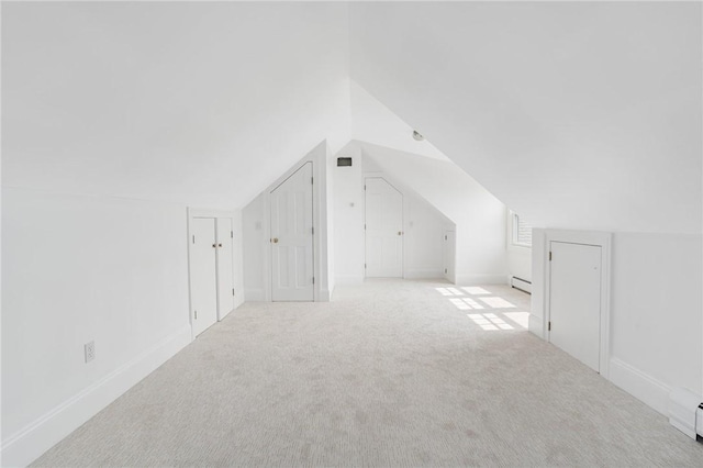 additional living space featuring light colored carpet, lofted ceiling, and a baseboard radiator