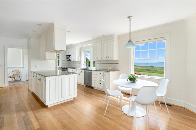 kitchen with white cabinetry, hanging light fixtures, dark stone counters, stainless steel appliances, and decorative backsplash