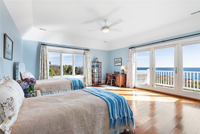 bedroom with access to outside, french doors, a water view, hardwood / wood-style flooring, and ceiling fan