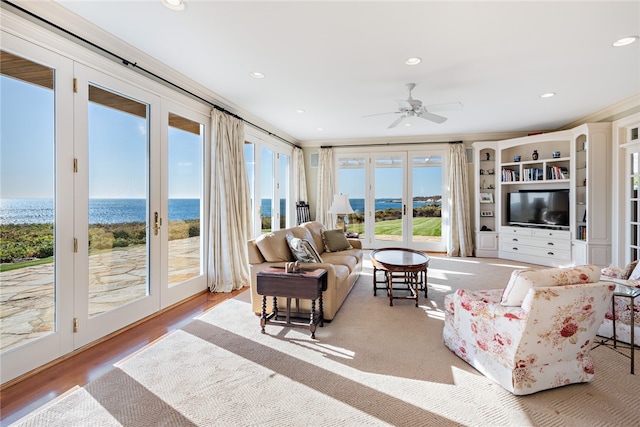 living room featuring ornamental molding, ceiling fan, a water view, and hardwood / wood-style flooring