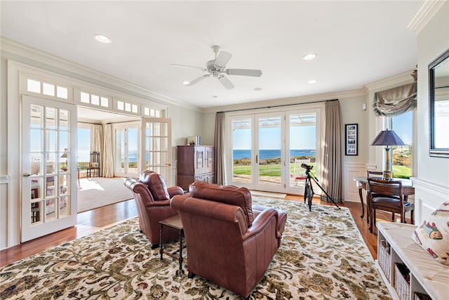 living room with plenty of natural light, wood-type flooring, crown molding, and a water view