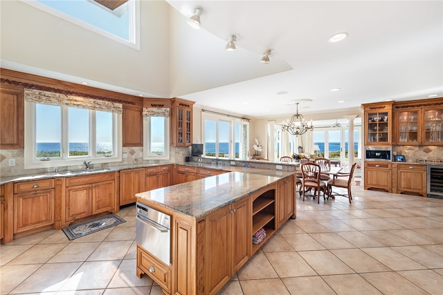 kitchen with a notable chandelier, plenty of natural light, backsplash, and light tile flooring