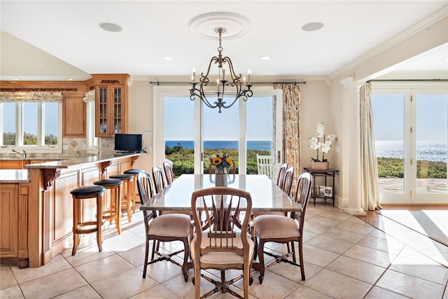 tiled dining room with a water view, sink, crown molding, and an inviting chandelier