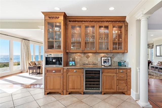 bar featuring a water view, decorative columns, tasteful backsplash, wine cooler, and ornamental molding