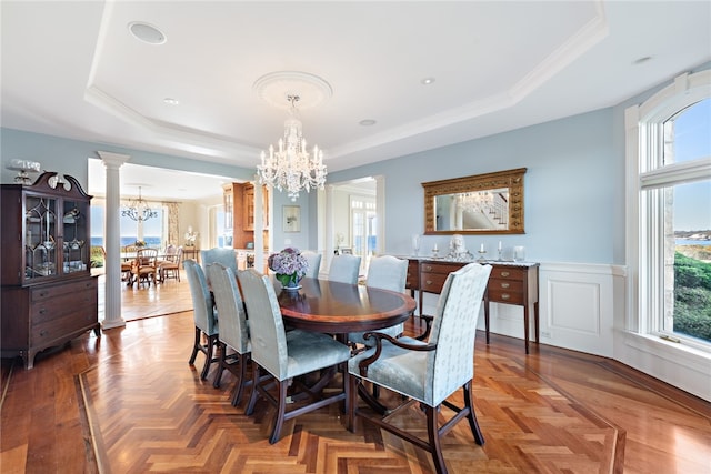 dining space with plenty of natural light, an inviting chandelier, decorative columns, and parquet flooring