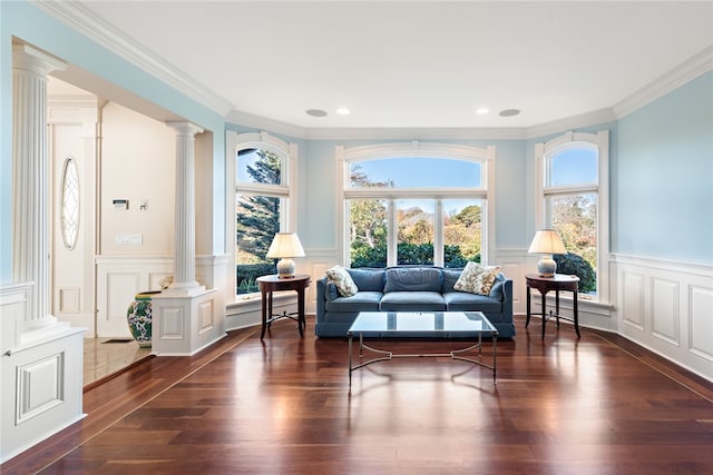 living area featuring ornamental molding, decorative columns, and dark wood-type flooring