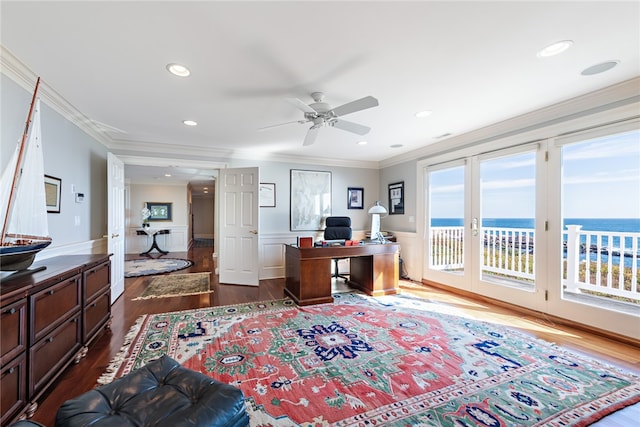 home office with ceiling fan, a water view, hardwood / wood-style flooring, and crown molding