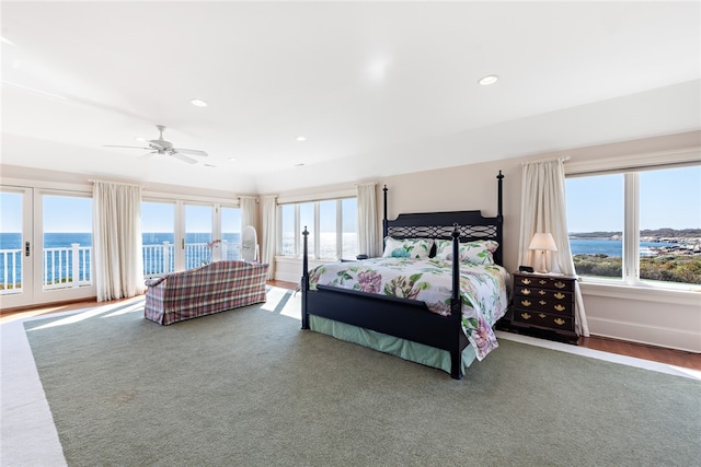 bedroom with multiple windows, a water view, ceiling fan, and access to outside