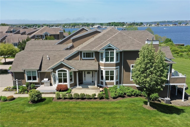 view of front facade featuring a front lawn and a water view