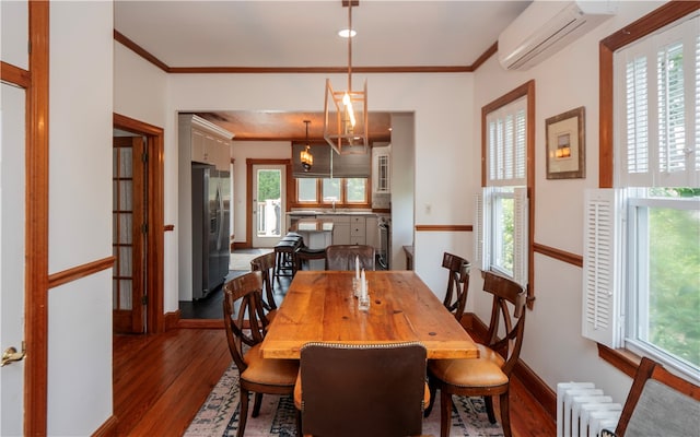 dining room featuring radiator, sink, crown molding, dark hardwood / wood-style floors, and a wall mounted AC