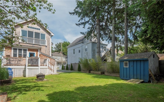 rear view of house featuring a yard, a balcony, an outdoor fire pit, and a storage shed