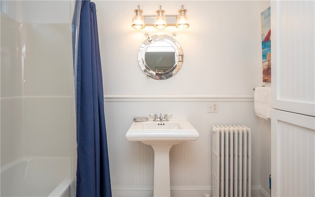 bathroom with radiator, shower / bath combo with shower curtain, and sink