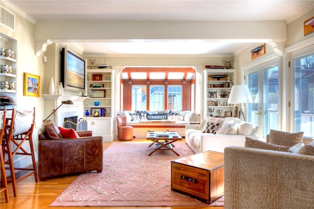 living room featuring a wealth of natural light, built in shelves, wood-type flooring, and french doors