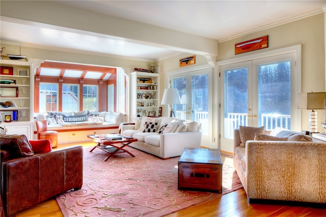 living room with french doors, ornamental molding, built in shelves, and hardwood / wood-style floors