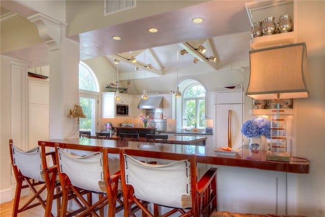 kitchen featuring paneled built in fridge, lofted ceiling with beams, white cabinets, hardwood / wood-style floors, and tasteful backsplash