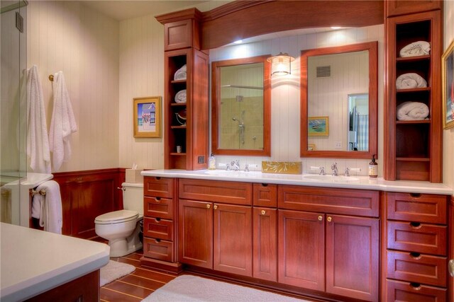 bathroom featuring dual bowl vanity, toilet, and wood-type flooring